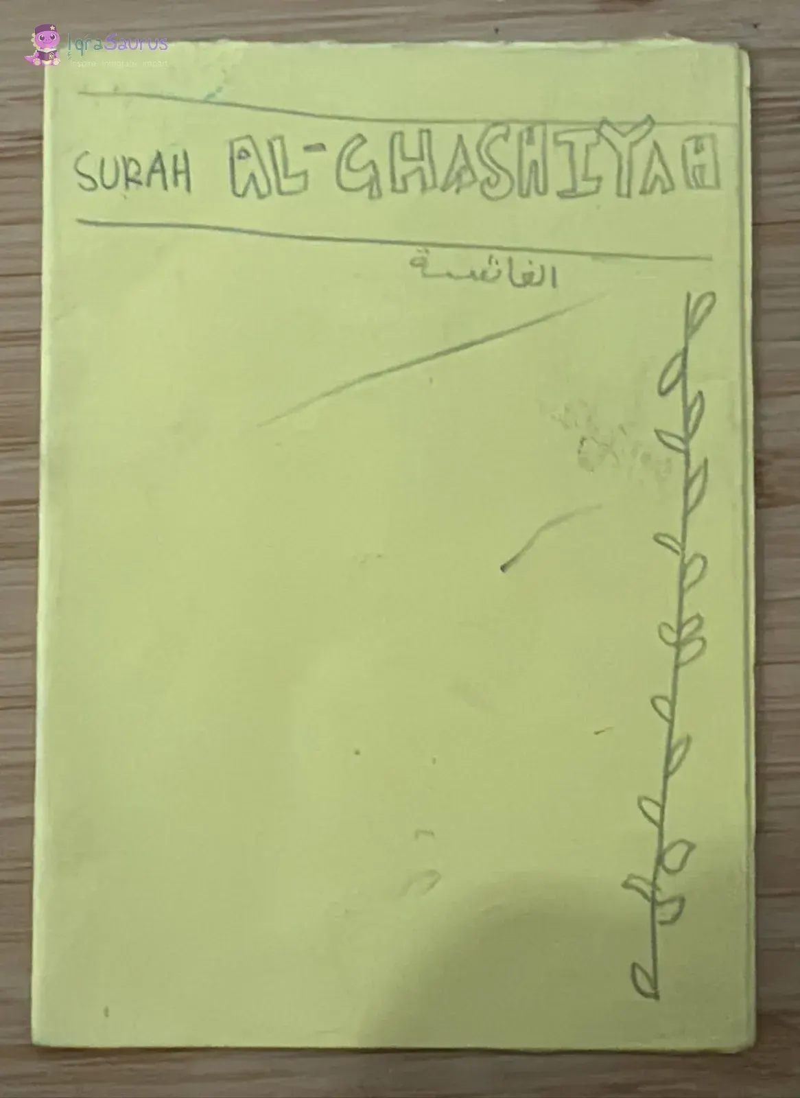 Yellow folded booklet cover reading Surah Al-Ghashiyah, with a drawn vine down one side