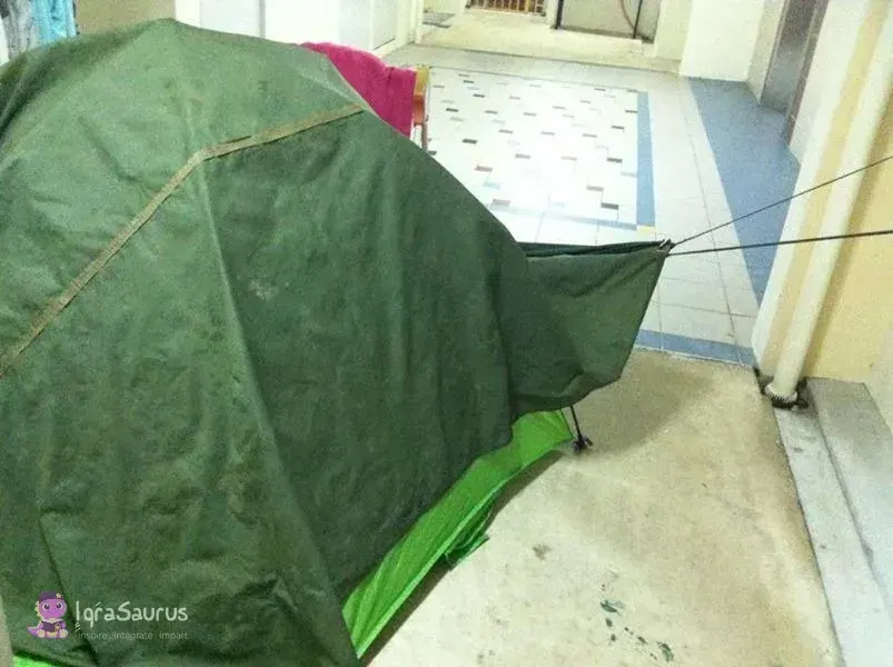 A green family tent pitched in the corridor outside a flat