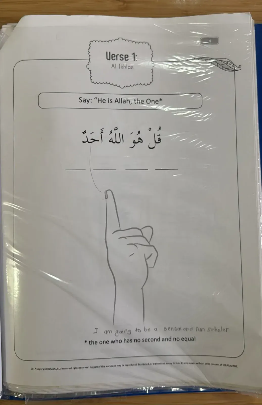 An Al-Ikhlas Doodle with Quran page with a drawing of a pointing finger and a child's handwritten line at the bottom