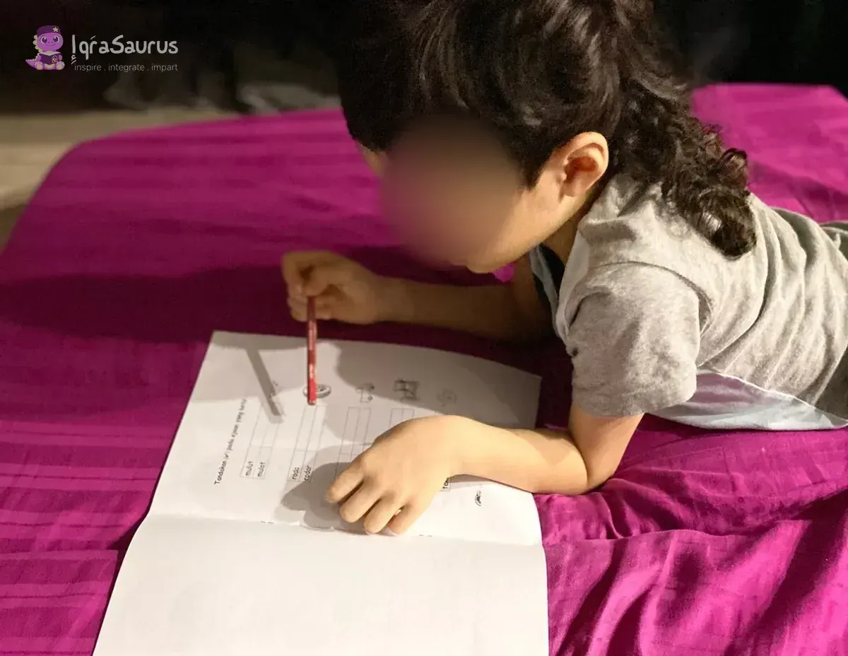 A boy lying on a bed working on a practice paper, with a practice-paper booklet in the front