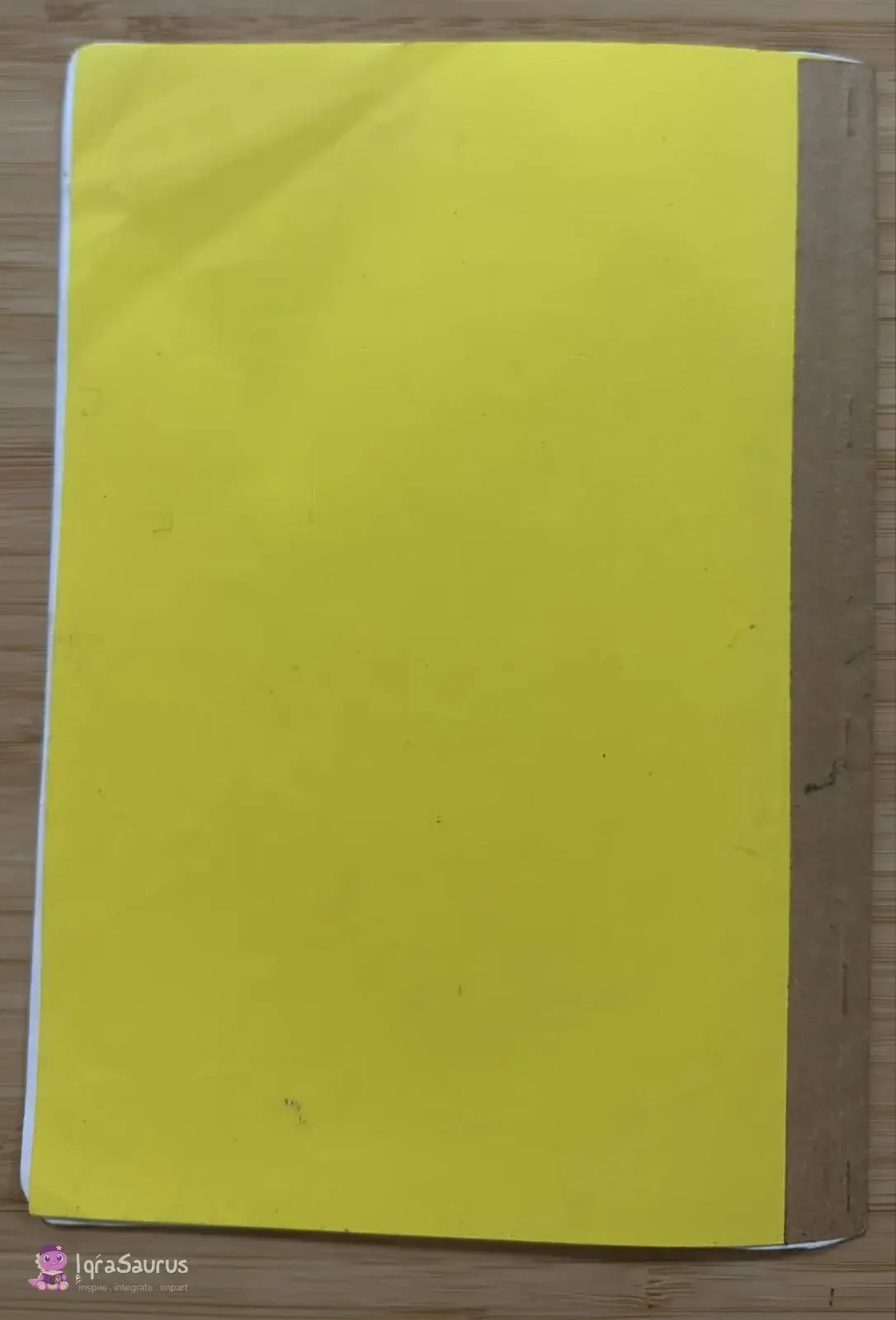 The plain yellow back cover of the notebook with a brown taped spine.